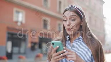 一个穿着蓝白相间条纹连衣裙的可爱女人站在老城街上，用智能手机上的<strong>app</strong>。美丽的